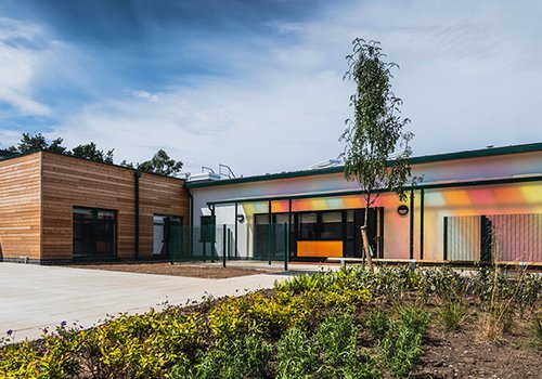 Image of the outside of the The Bridge SEN School, with brightly coloured sun shade to the front of the building