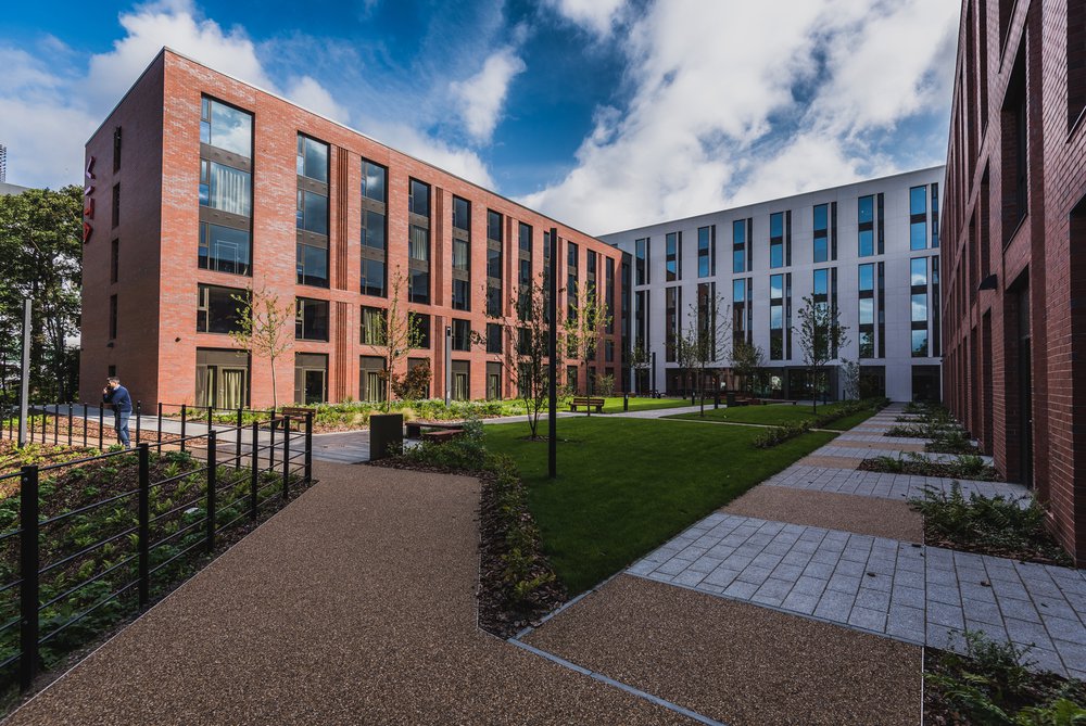 Wide shot of VITA Birmingham, three buildings in a U shape with a grass and paving area in the middle