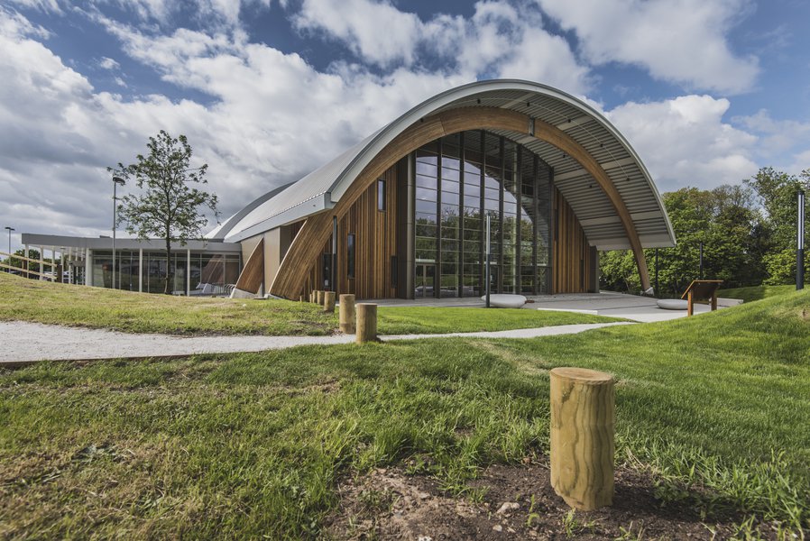 A view from the outside of the Montem Ice Arena in Slough, the building has a curved roof and surrounded by green public space