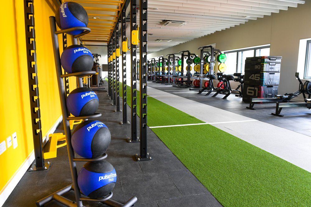 Gym area at Southampton Solent Sports Complex, image focuses on dumbells which are next to a bright yellow wall