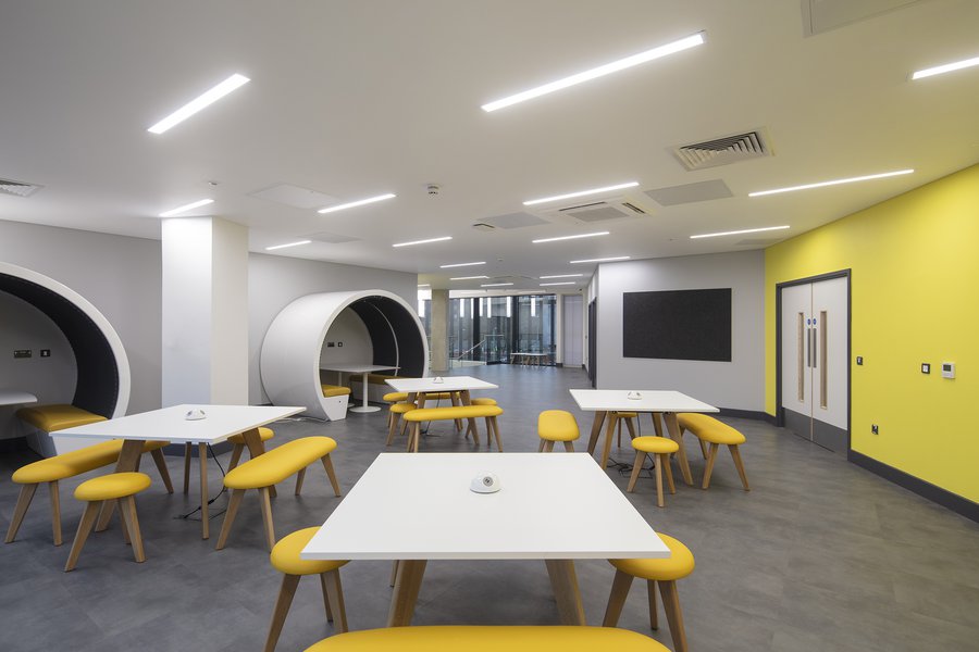 Cafe area at South Essex College in Basildon, with yellow walls, furniture and round seating pods