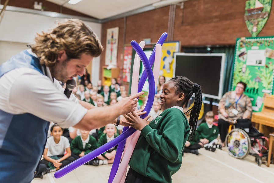 A magician performs for a group of school children as part of the handover of a new school building