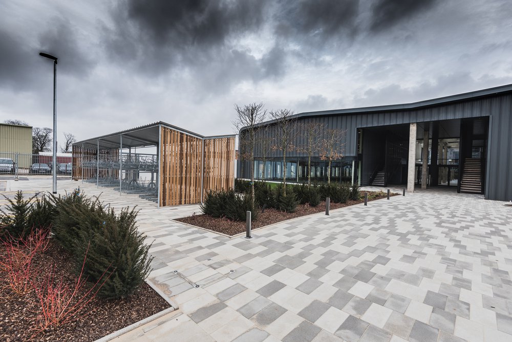 Image of the front entrance of the Unity Campus building in Sawston, Cambridge that shows the block paving and planting to the front