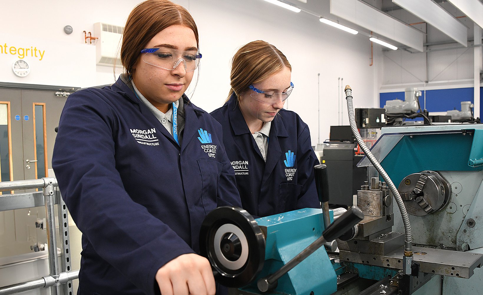 Two students of the Energy Coast UTC are pictured working at an industrial machine