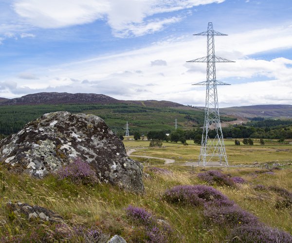 A photograph of a countryside landscape, with electricity towers visible in the foreground and background