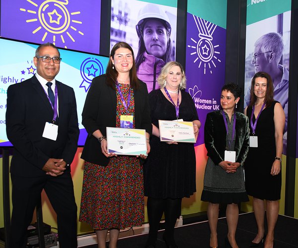 A group of five award winning colleagues from various companies stand on stage at the Women In Nuclear awards. Among them stands Morgan Sindall Infrastructure SHEQ manager Claire Morfoot, third from left