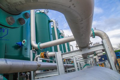 A series of large pipes trail into the distance, connected to large tanks