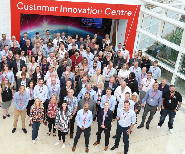 A large group of Morgan Sindall Infrastructure colleagues stand assembled in a group as part of a company event. Photographed from above, they smile at the camera