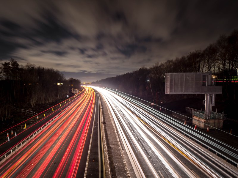 a road at night, lights of cars blurred into long streams